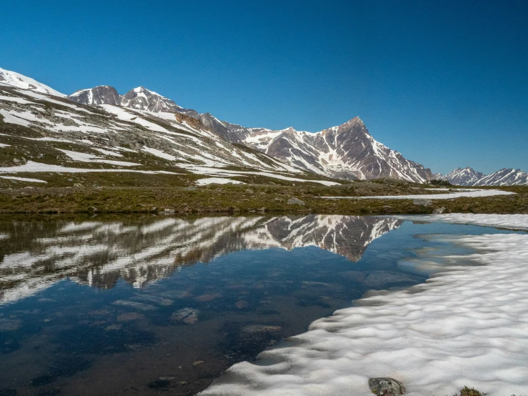 snow blankets and mountains around a small lake