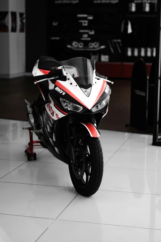 the red, white and black motorcycle is parked on the tile