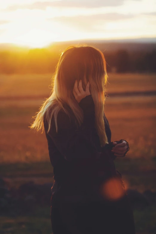 a person is talking on her cellphone at sunset