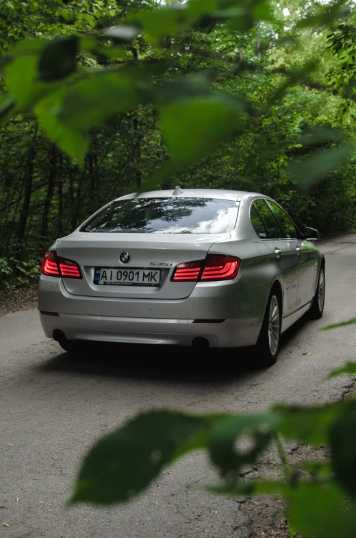 a car driving on the road past a wooded area