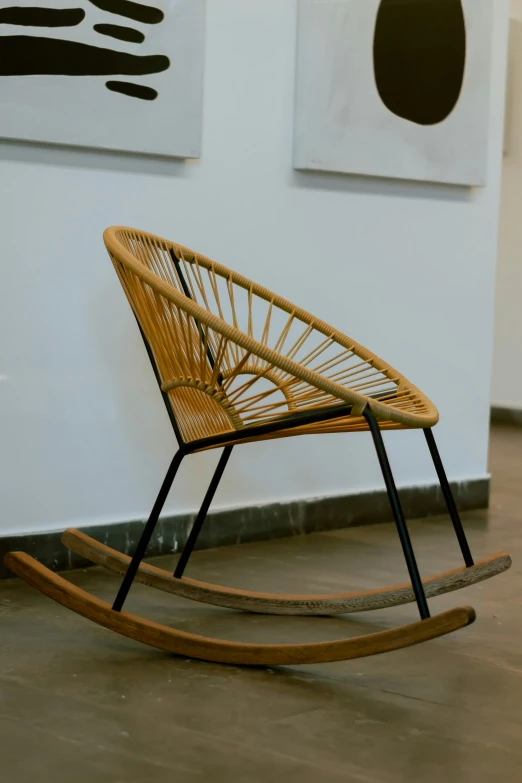 a chair in front of a wall next to two large paintings