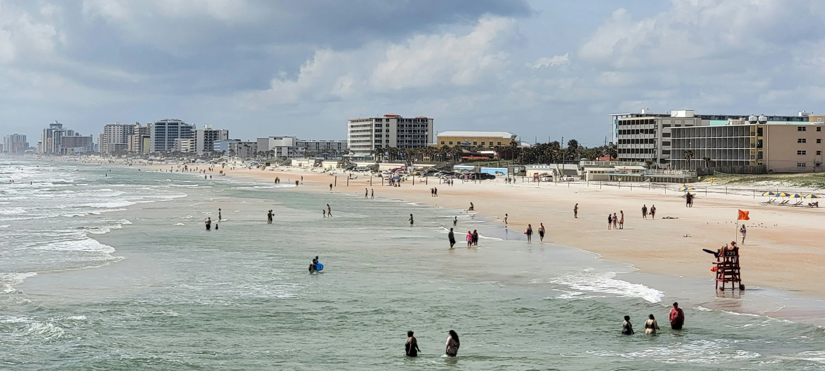 a sandy beach next to the ocean with people walking