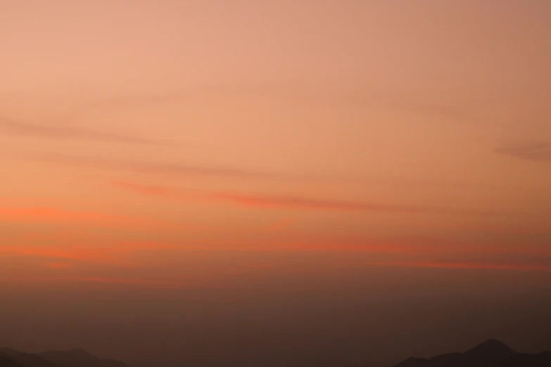 a sunset is seen above the mountains in the distance