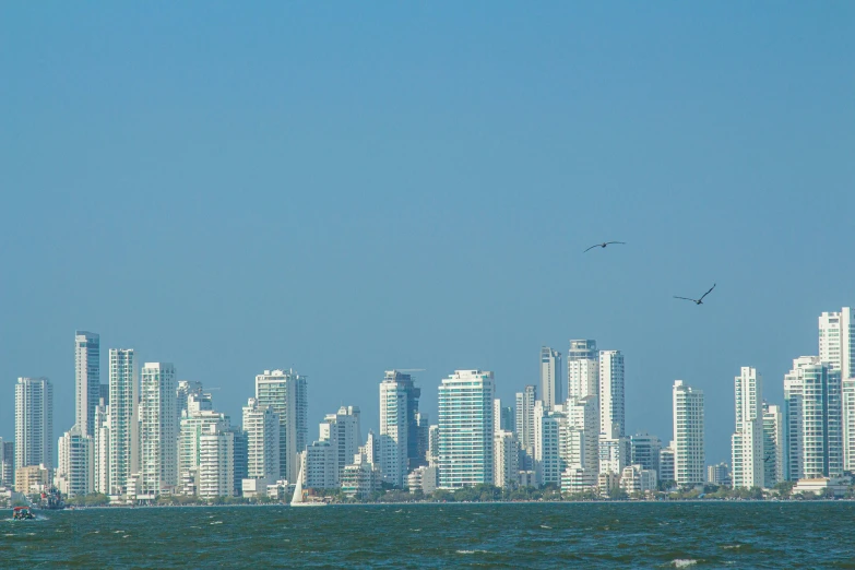 a sail boat out on the water with buildings behind it