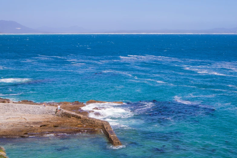 the view of the blue ocean with waves coming in and out from the rocks