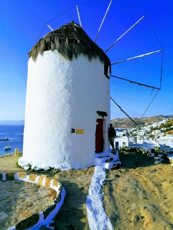 a wind mill with red door next to water