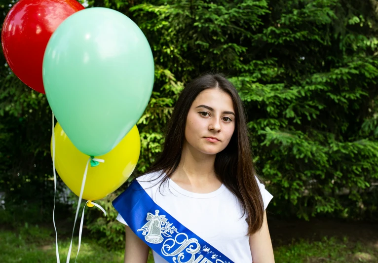 the girl is holding two balloons and posing for a po