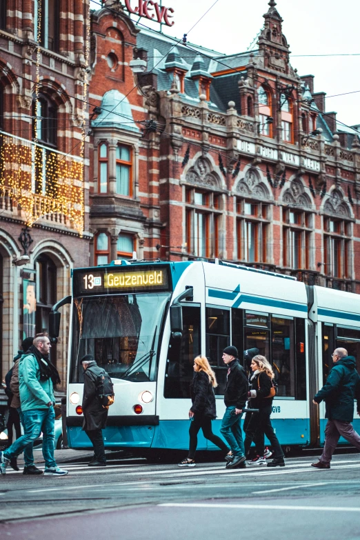 several people crossing the street as a bus passes by