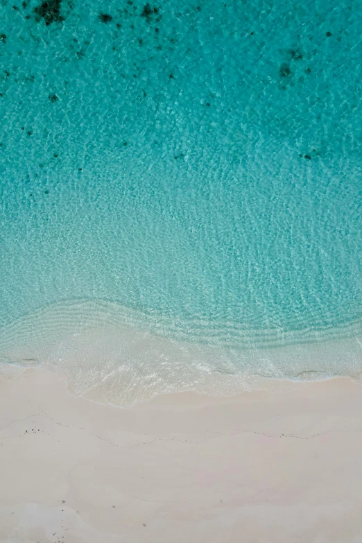 an aerial view of water and beach sand