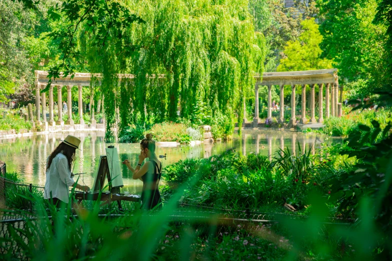 a man and woman in wedding attire sitting on the side of a pond