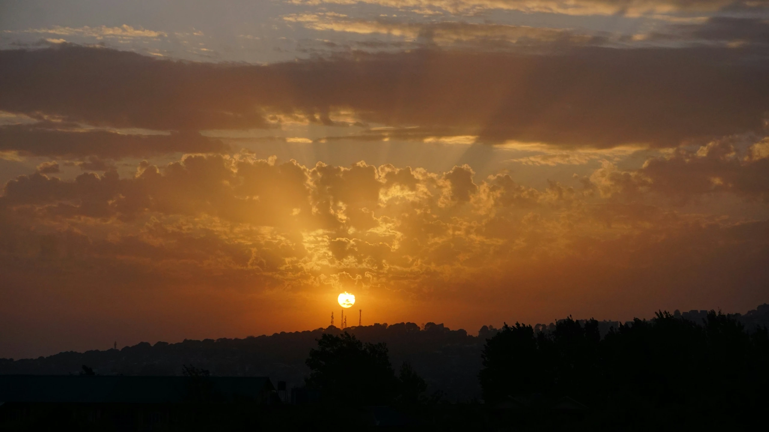 a sunset with clouds and some trees