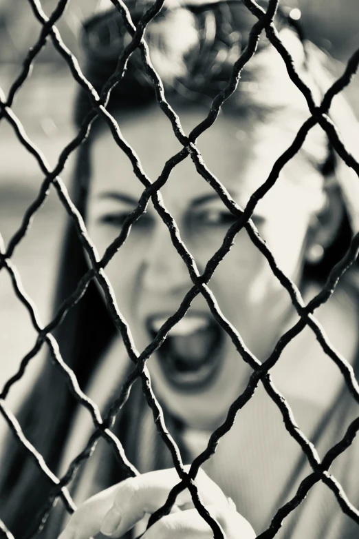 a girl holding soing through a fence with her hand