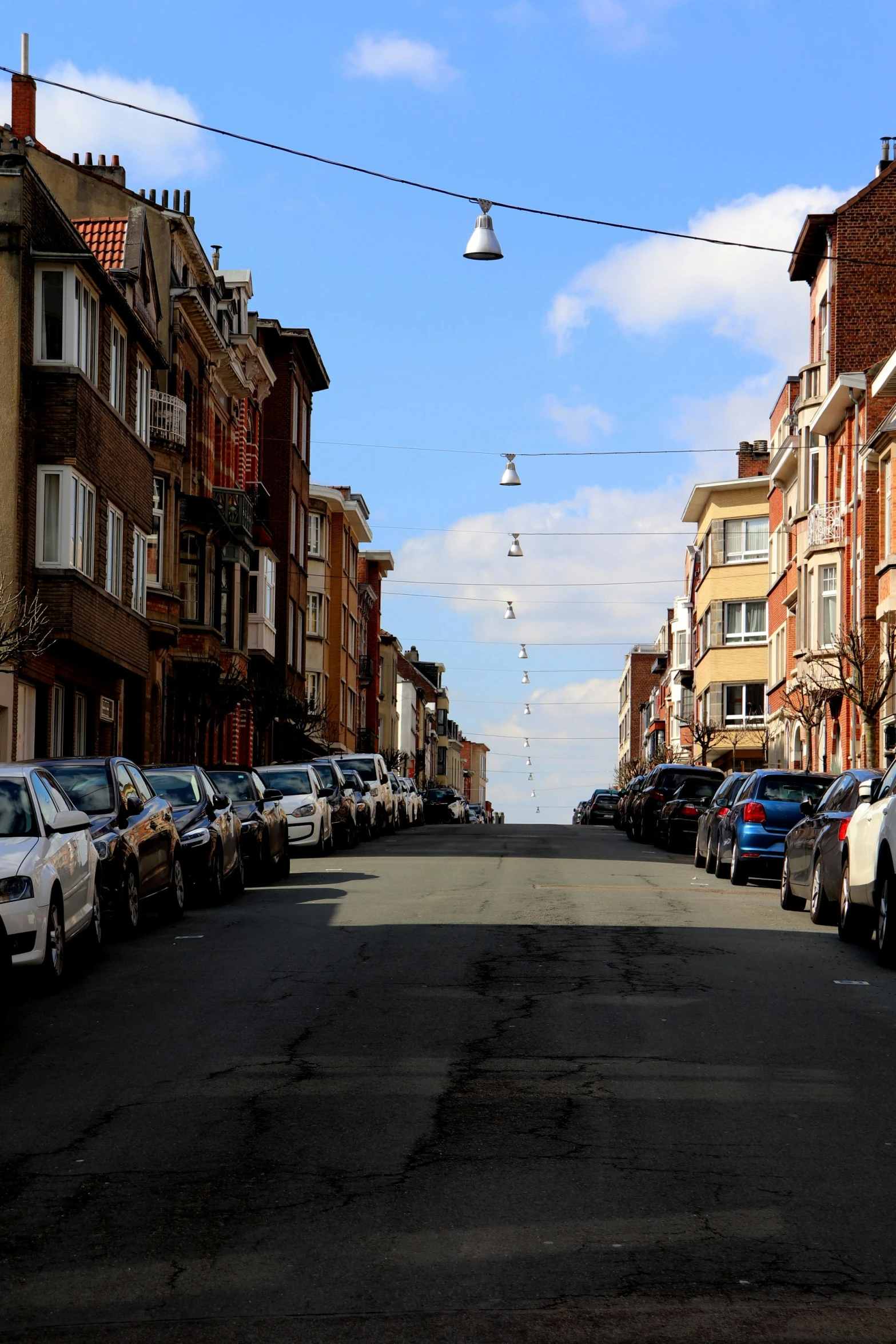 a long street with a bunch of cars lined up on the sides