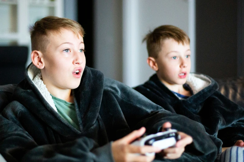 two boys are playing a video game in the living room