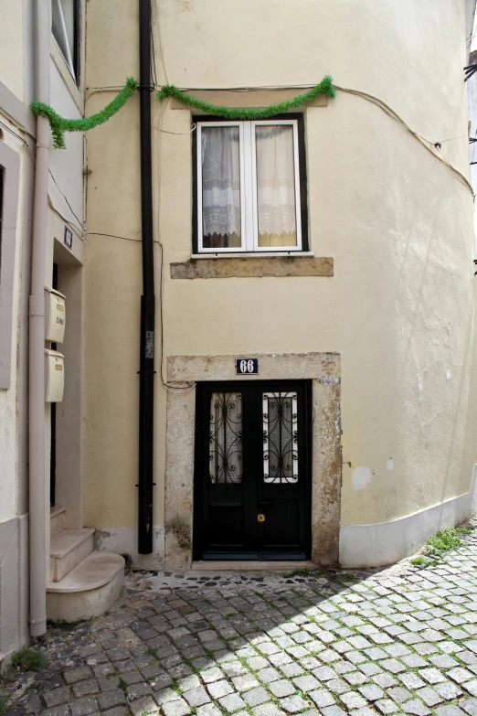 an alleyway has a black door with glass panels and two windows