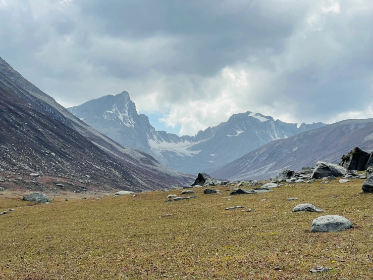 an open field with some rocks near mountain side