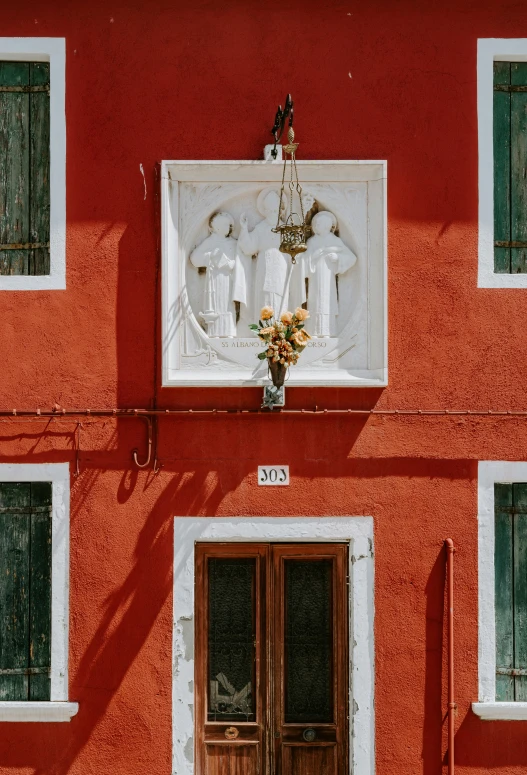 some statues on a red building with green doors