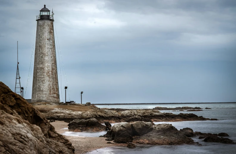 a light house on the shore with a rocky cliff below