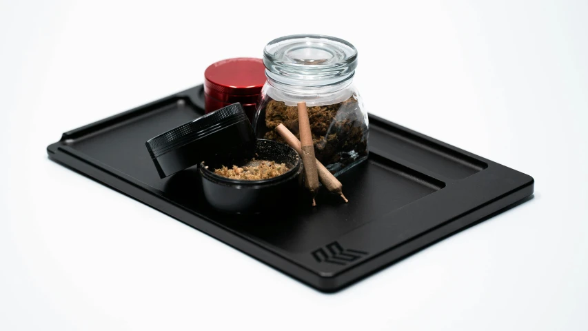 a glass jar filled with spices sitting on top of a black tray