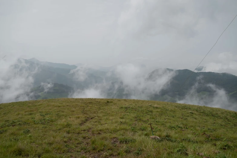 a hill covered in green grass surrounded by fog