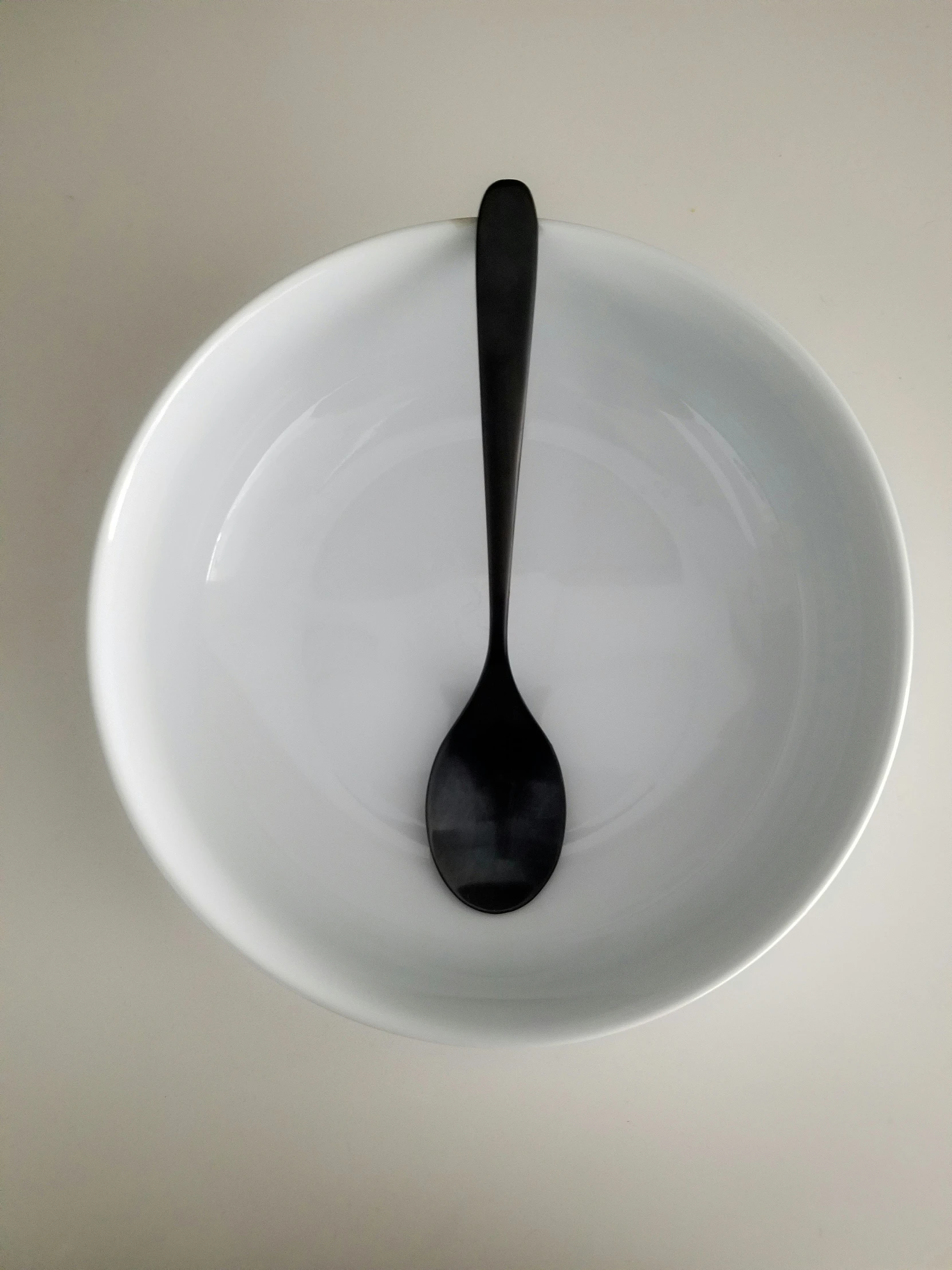 a spoon in a white bowl above a gray floor