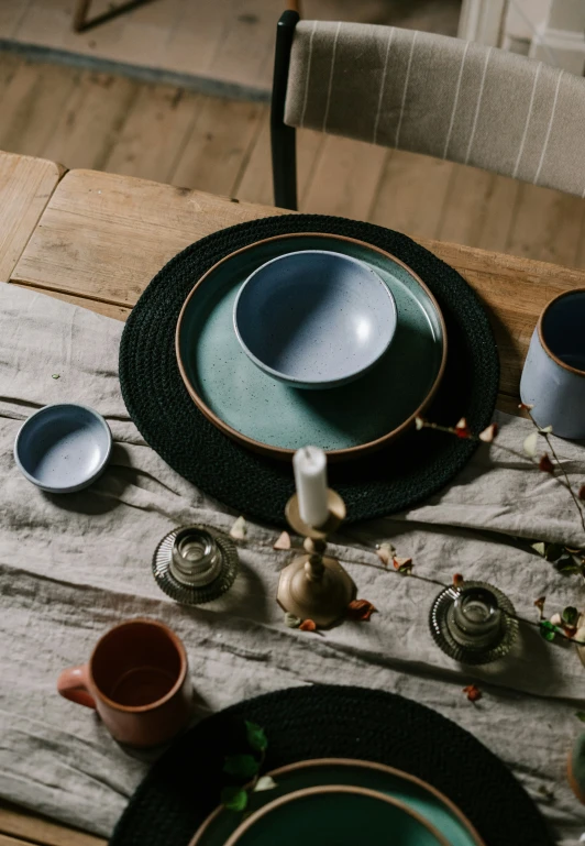 a table with plates, cups and spoons and coffee pot