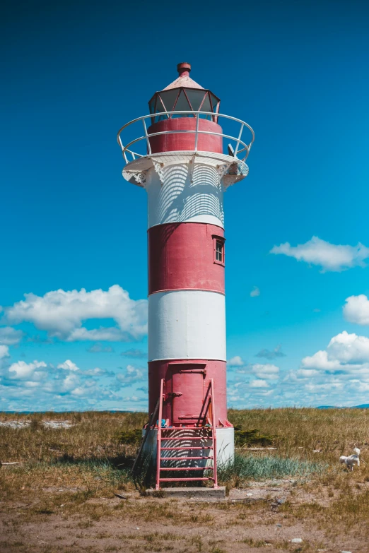 a red and white lighthouse sitting in the middle of an empty field