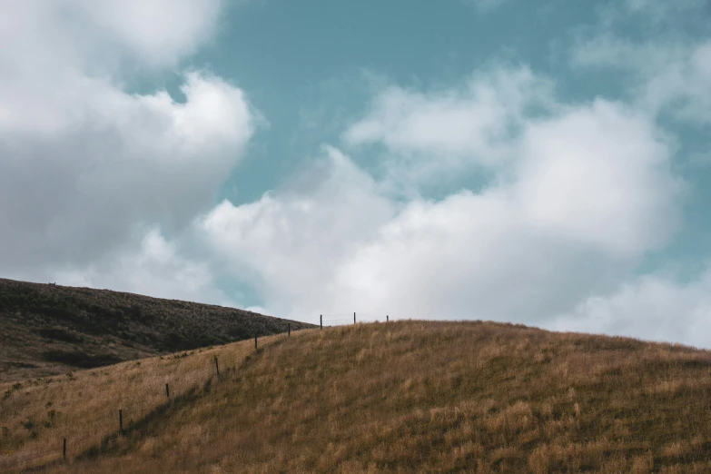 a hill with grass and a fence in the middle