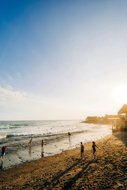 a couple of people are walking on a beach near water