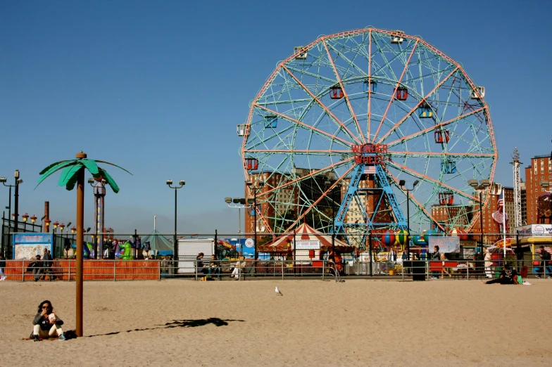 a large ferris wheel on the beach and some people