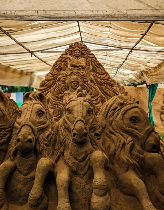 statues of people carved with sand under a canopy