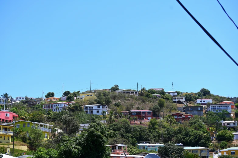 a hill in front of some houses is seen with trees and power lines on it