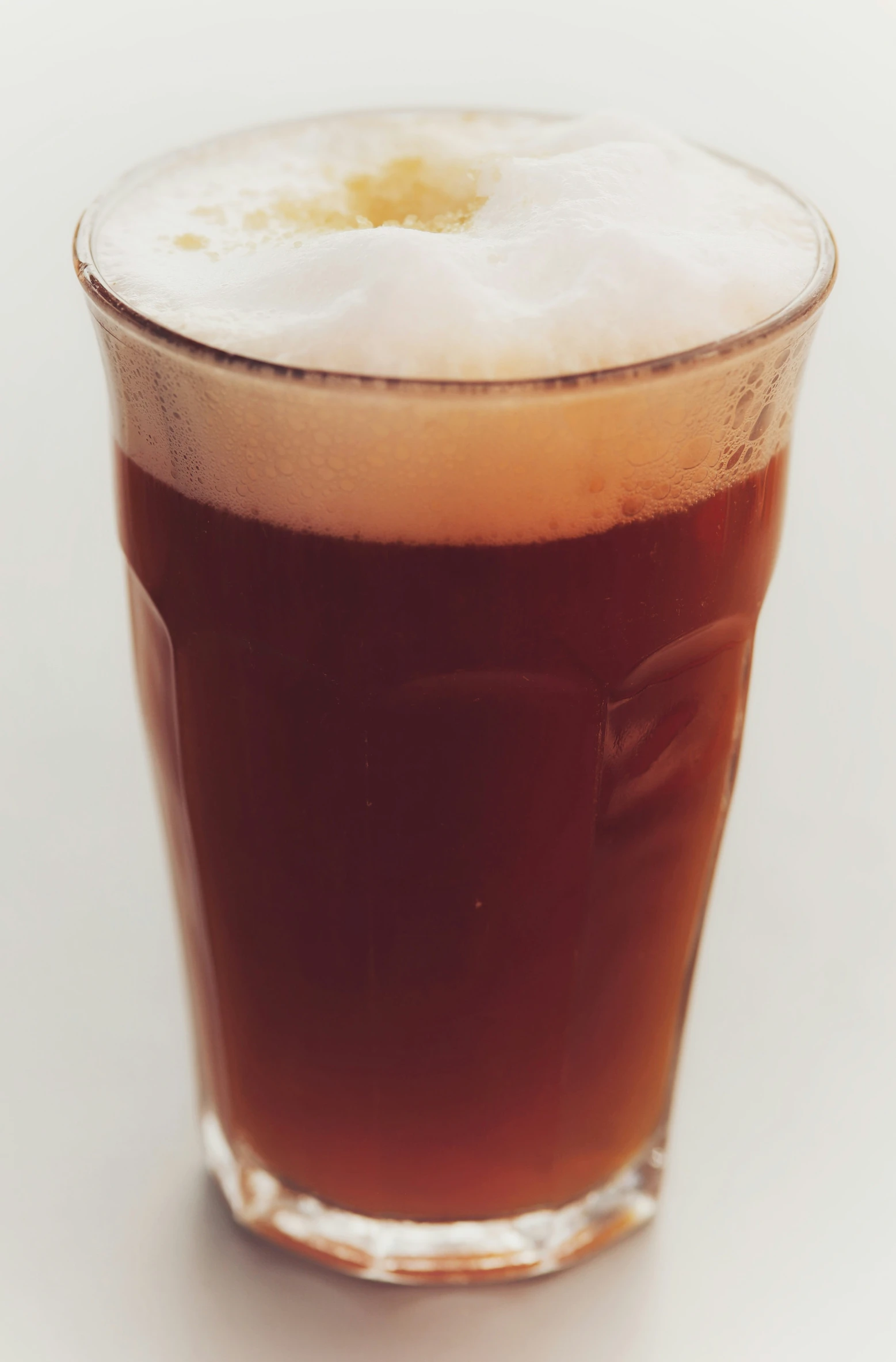 an alcoholic drink in a tall glass sitting on a white surface