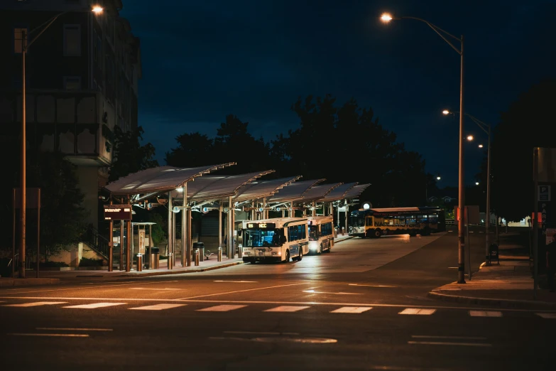 a bus stop on a street corner lit up at night