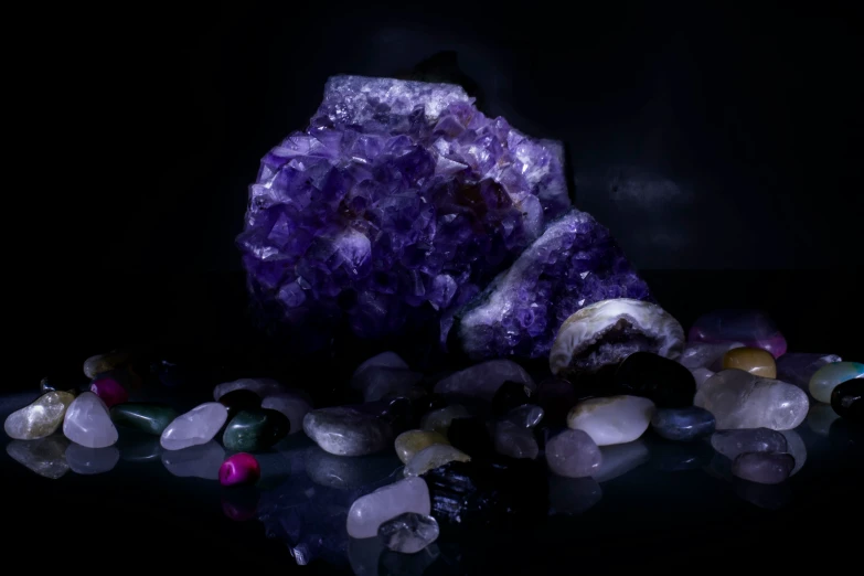 some crystal rocks and purple and pink stones on a reflective surface