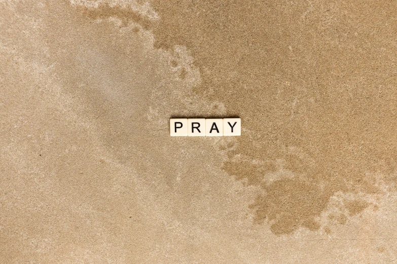 the word pray is embedded in the sand