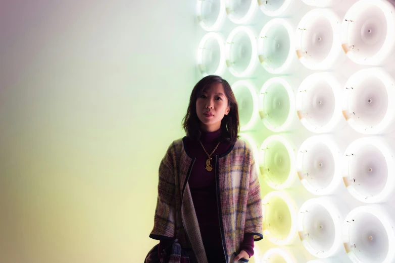a girl is standing next to a neon wall