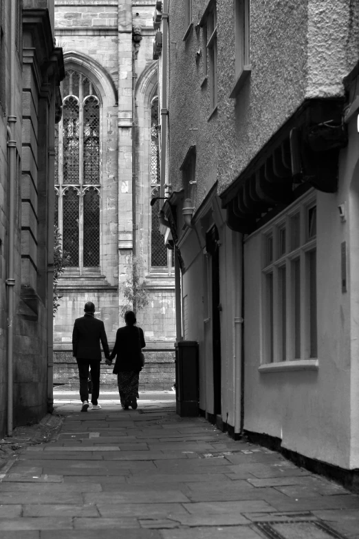 two people walking down a stone paved street holding hands