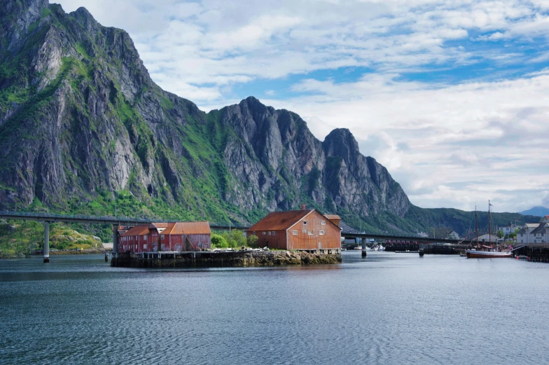 the landscape shows a bridge and buildings with mountains behind them