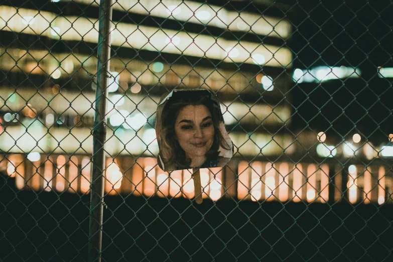 a woman looks through a fence at night