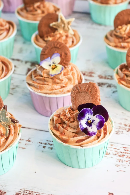 several cupcakes topped with frosting and a pansy flower