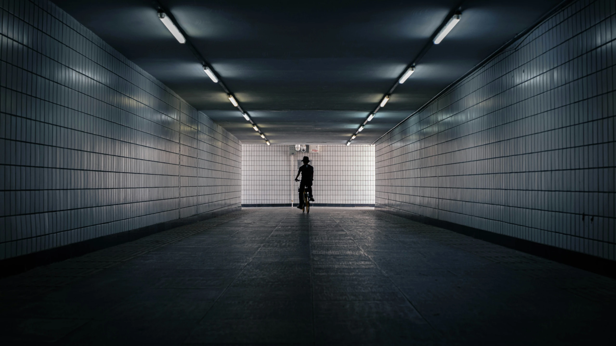 person in a dark alley with light coming through the walls