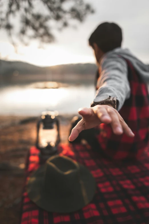 a man holding his hand out to someone sitting at a picnic table with a bottle