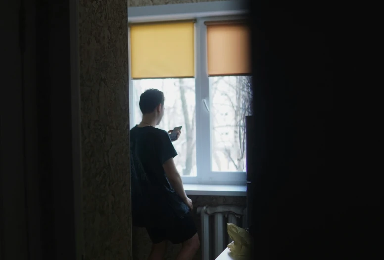 a person standing in a room looking out a window