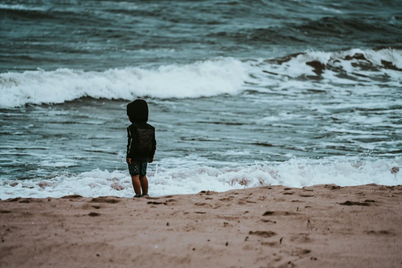 little boy on a beach looking out to the ocean