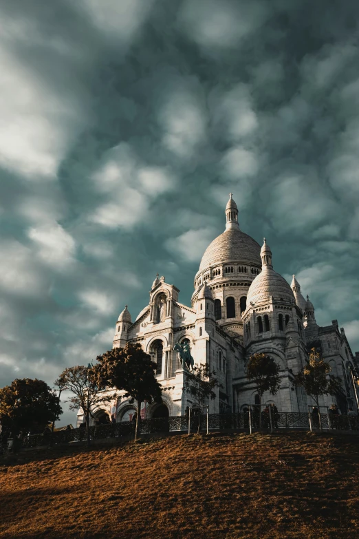 the large cathedral is situated on a hill under cloudy skies