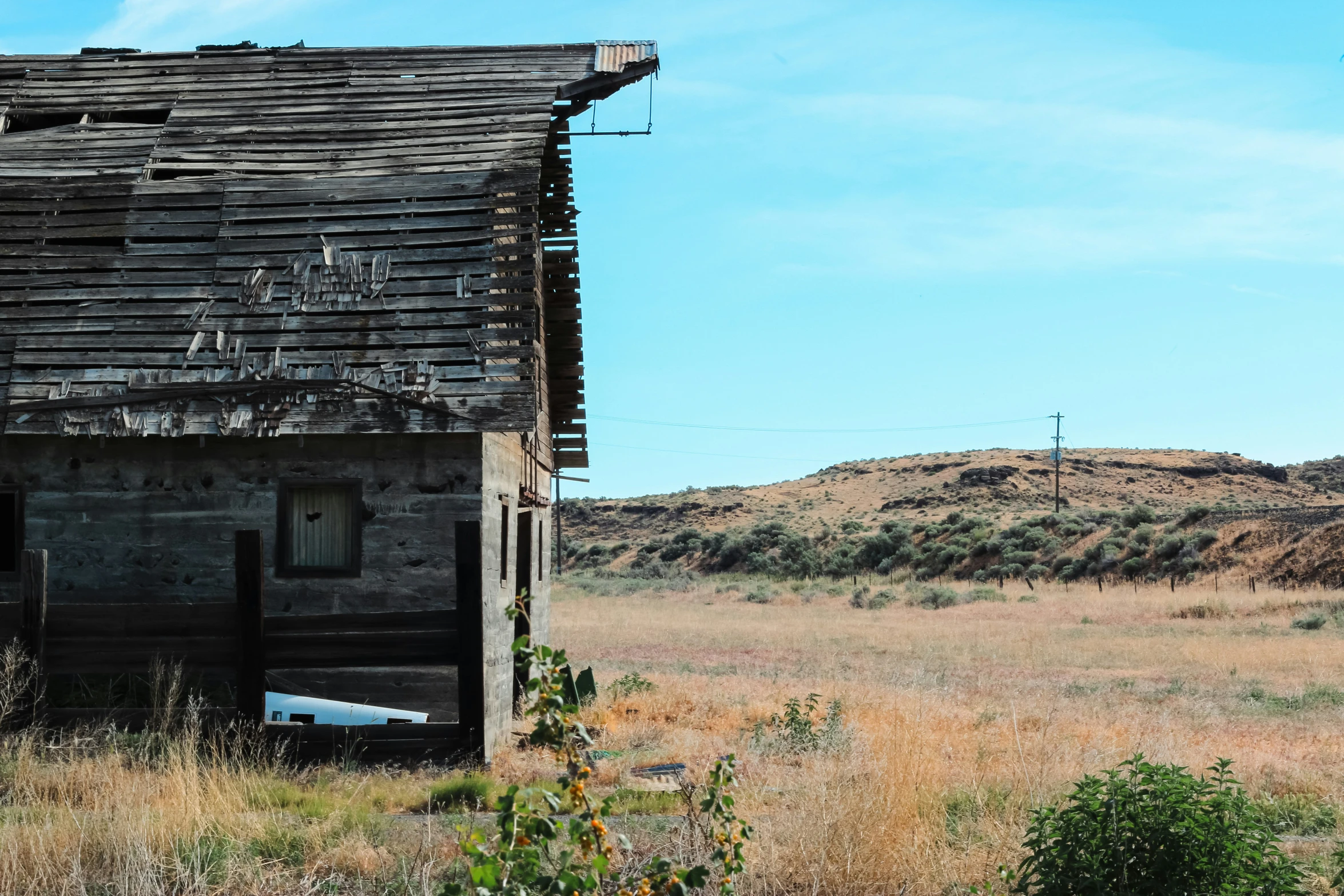 an old shed sitting in a field of brown grass