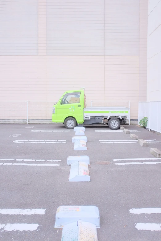 a green truck is parked next to a building