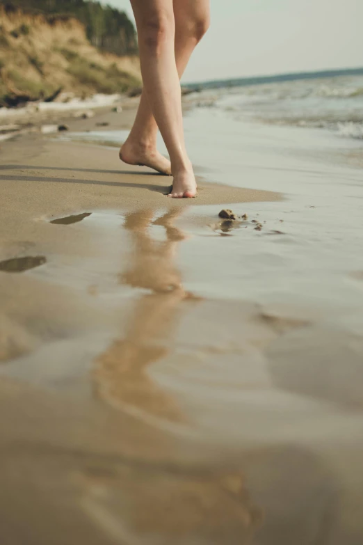 close up of a barefoot person walking on the beach