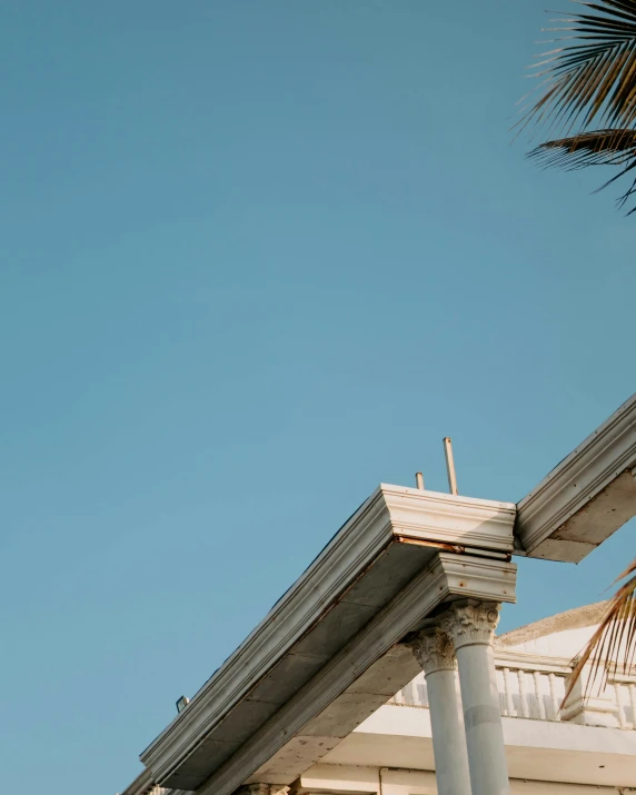 a cross standing on top of a roof with a palm tree nearby